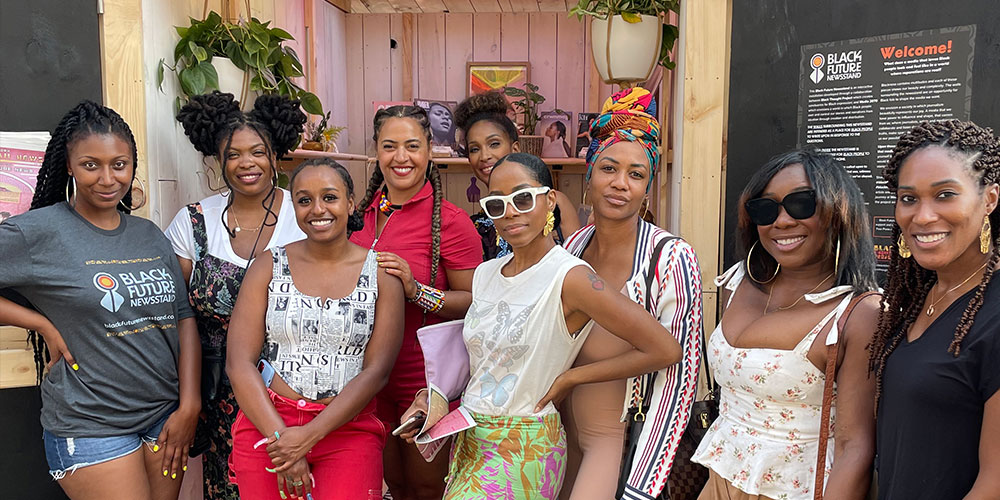 Photo of co-creators in front of the Black Future Newsstand